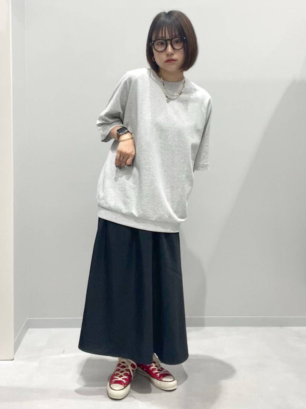 グレー系のTシャツ/カットソー、ブラック系のスカート、グレー系のネックレスを着用したレディースの春コーディネートの1枚目の写真