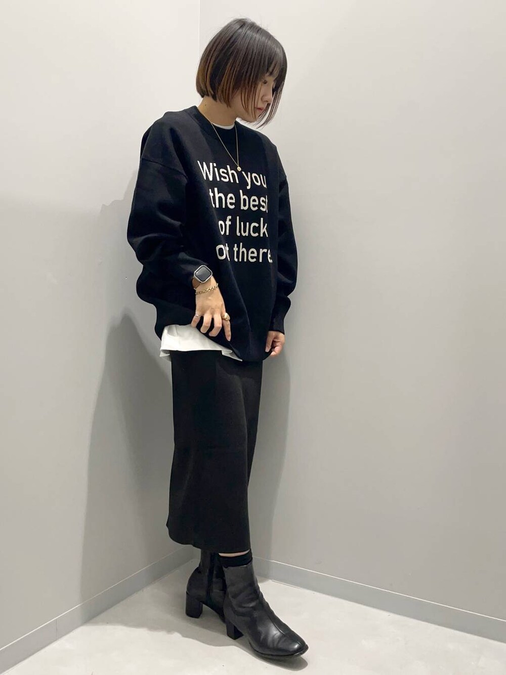 ブラック系のニット/セーター、ホワイト系のTシャツ/カットソー、ブラック系のスカートを着用したレディースの秋コーディネートの1枚目の写真