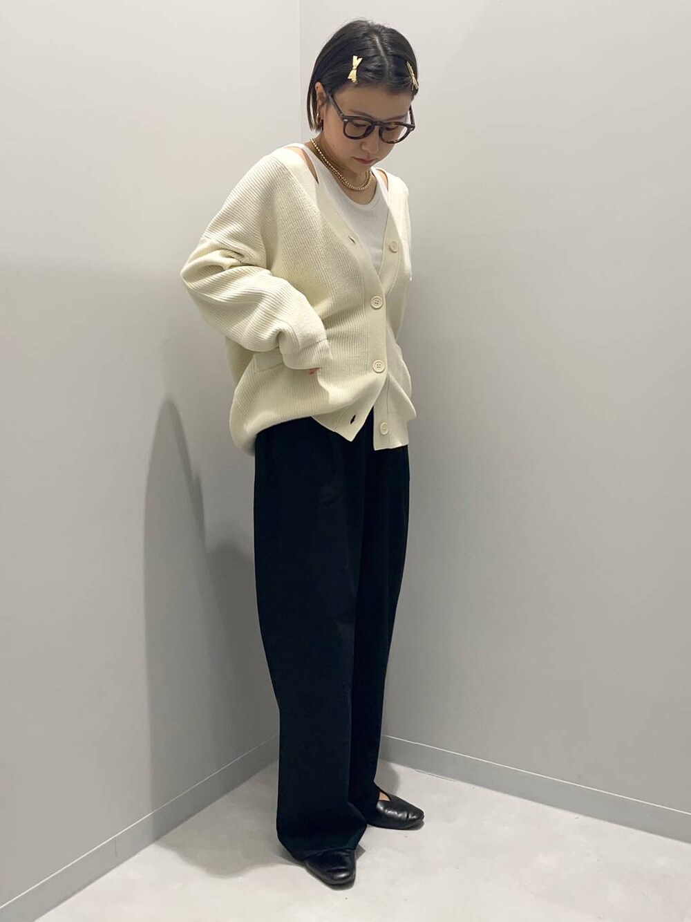 ブラック系のその他パンツ、ホワイト系のニット/セーター、イエロー系のバレッタ/ヘアクリップを着用したレディースの秋コーディネートの1枚目の写真