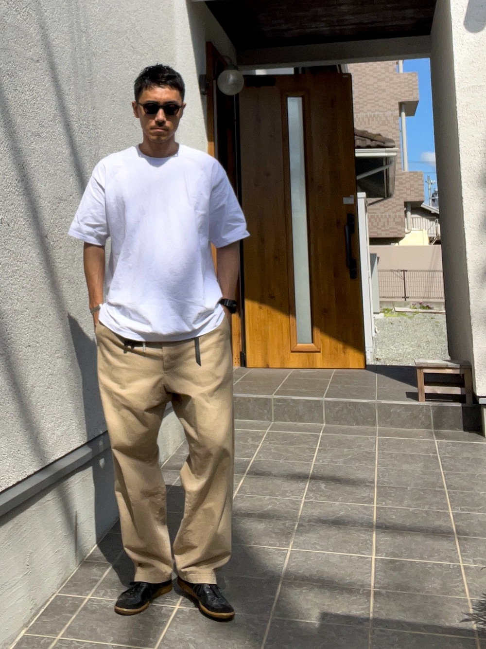 ブラック系のスニーカー、ホワイト系のTシャツ/カットソー、ベージュ系のチノパンツを着用したメンズの春コーディネートの1枚目の写真