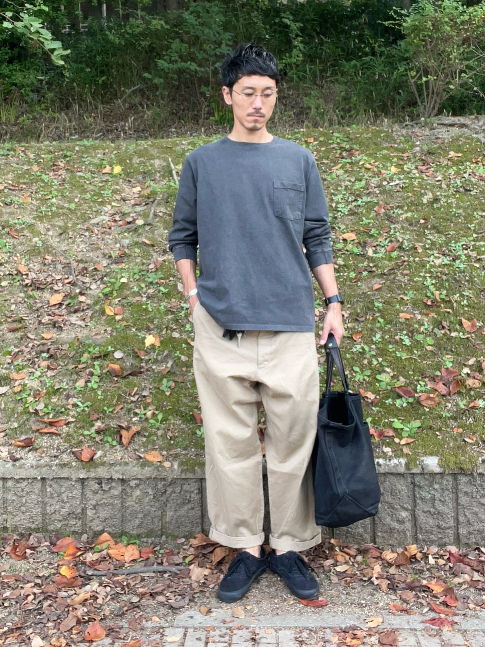 グレー系のTシャツ/カットソー、ベージュ系のチノパンツ、ブラック系のトートバッグを着用したメンズの秋コーディネートの1枚目の写真