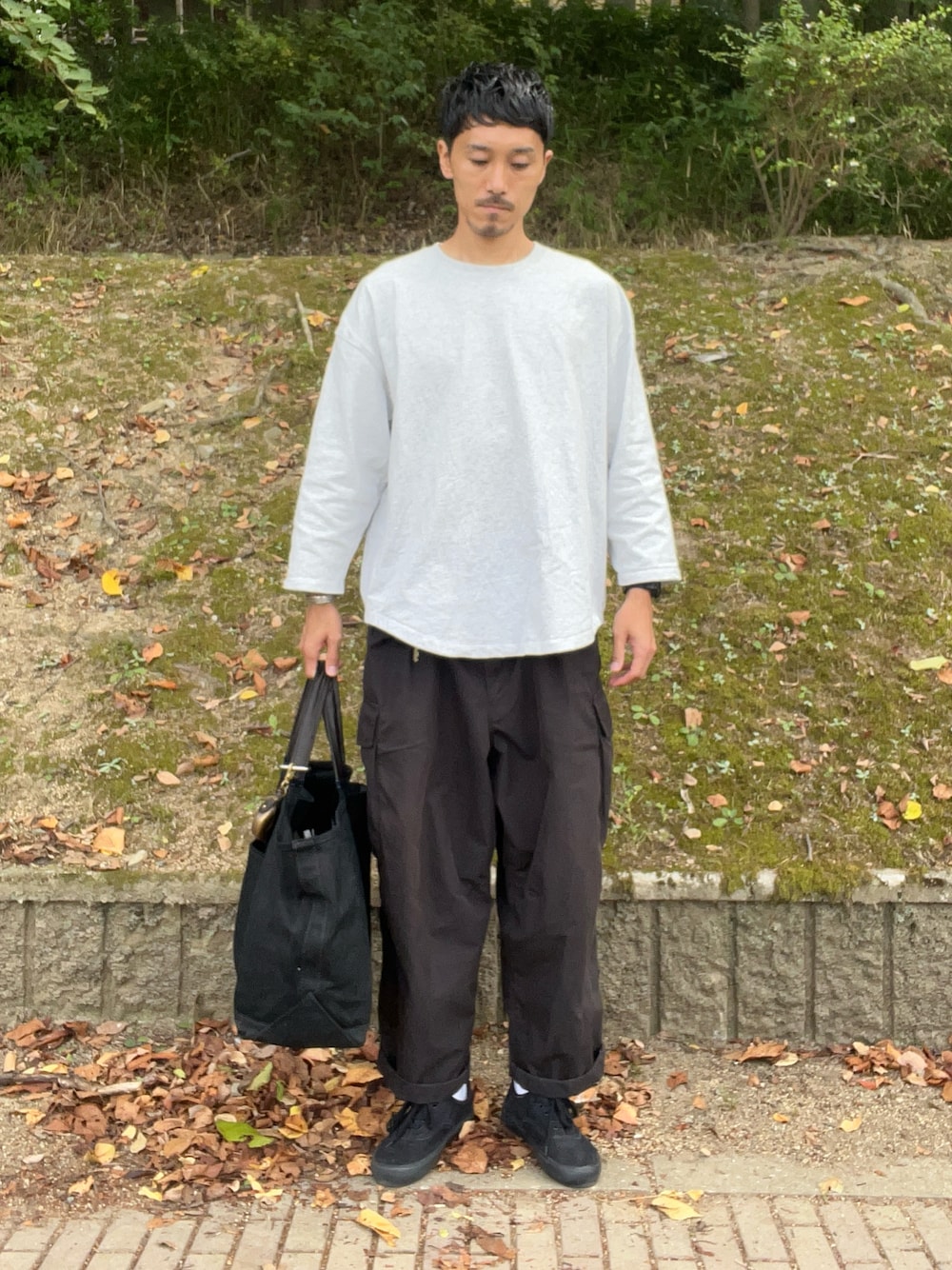 ホワイト系のTシャツ/カットソー、ブラック系のカーゴパンツ、ブラック系のトートバッグを着用したメンズの秋コーディネートの1枚目の写真