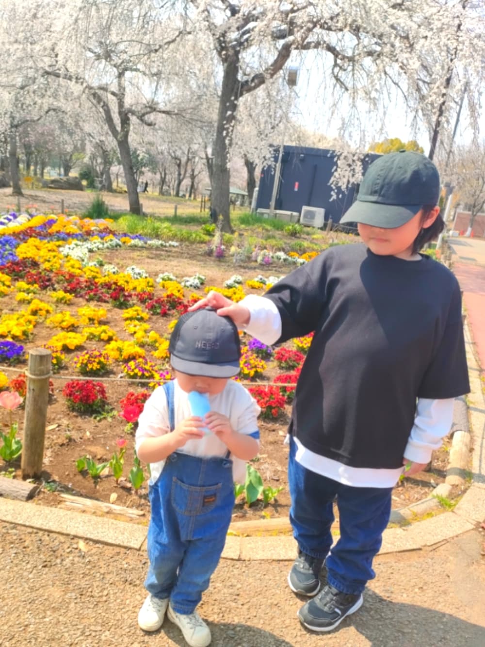 ブルー系のサロペット/オーバーオール、ホワイト系のスニーカー、ブルー系のデニムパンツを着用したキッズの春コーディネートの1枚目の写真