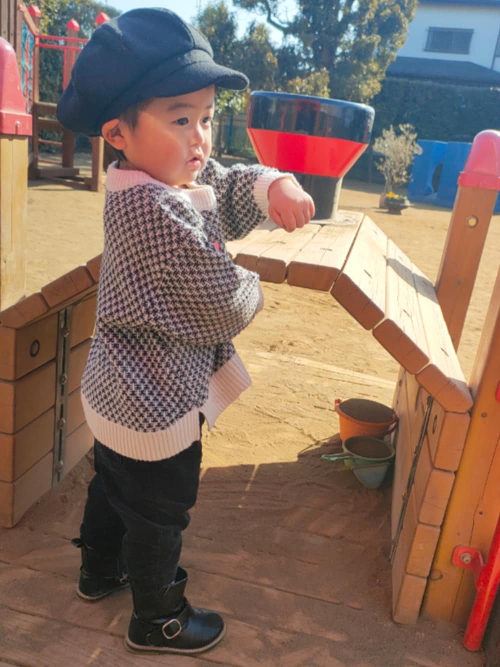 ホワイト系のカーディガン/ボレロ、ブラック系のその他パンツ、ブラック系のブーツを着用したキッズの冬コーディネートの1枚目の写真