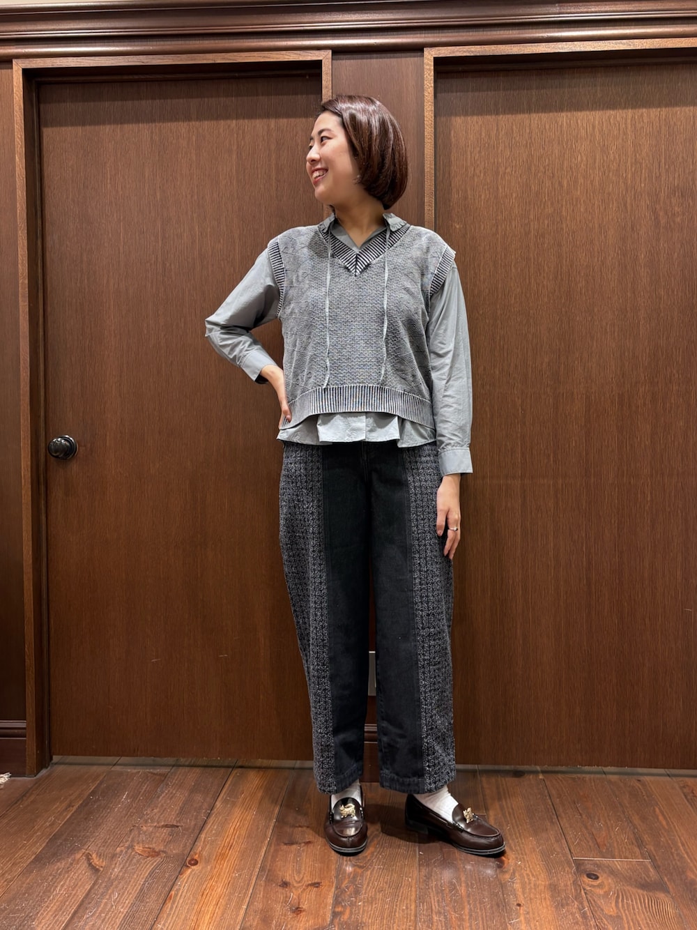 ブラック系のベスト、グレー系のシャツ/ブラウス、ブラック系のデニムパンツを着用したレディースの秋コーディネートの1枚目の写真