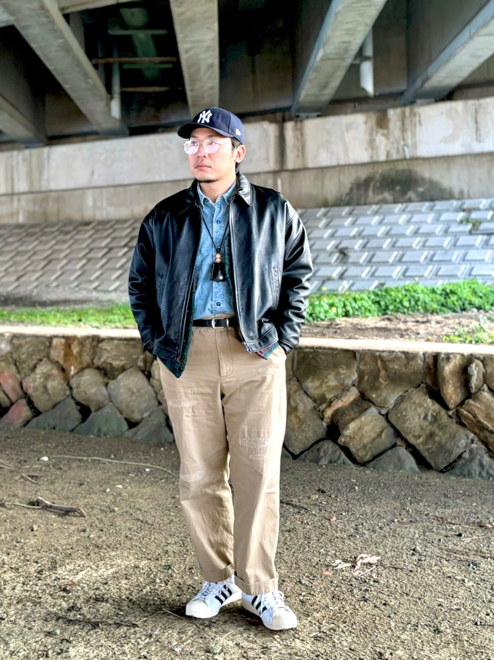 ホワイト系のスニーカー、ベージュ系のチノパンツ、ブラック系のブルゾンを着用したメンズの冬コーディネートの1枚目の写真