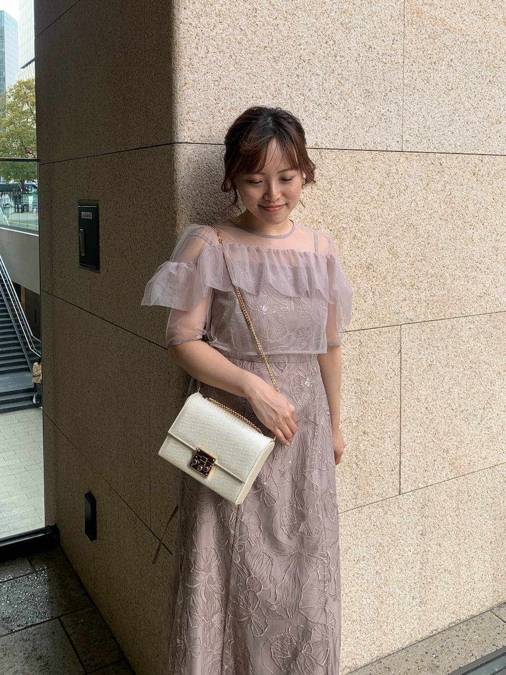 ベージュ系のドレス、ベージュ系のクラッチバッグ、ゴールド系のヘアピンを着用したレディースの春コーディネートの1枚目の写真