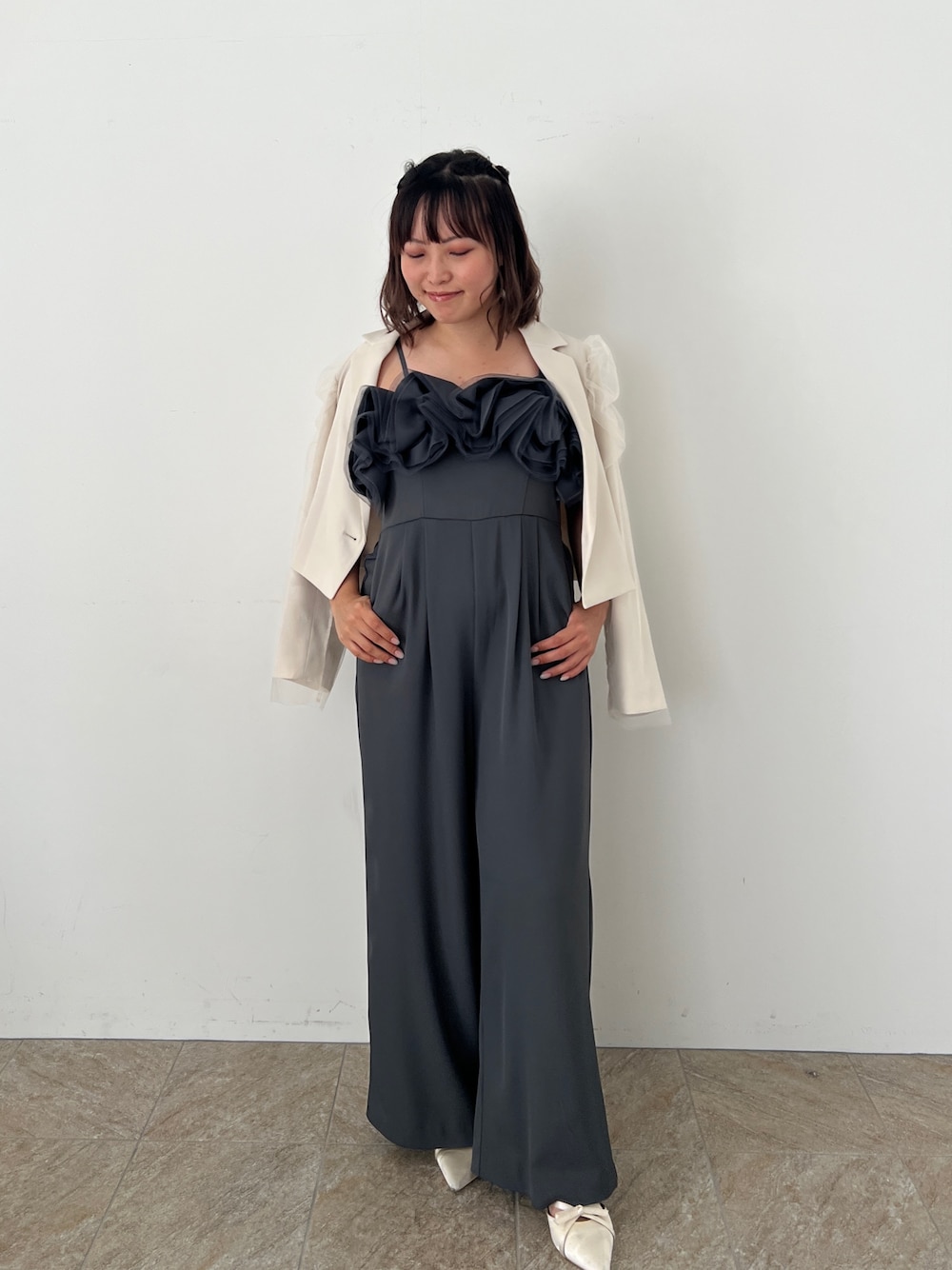 グレー系のパンツドレス、ベージュ系のパンプスを着用したレディースの秋コーディネートの1枚目の写真