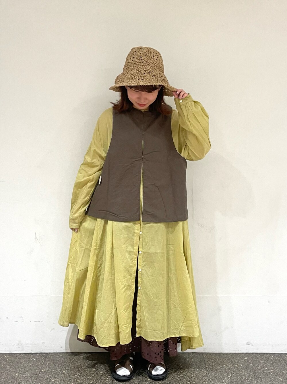 ホワイト系のベスト、イエロー系のワンピース、ブラウン系のスカートを着用したレディースの夏コーディネートの1枚目の写真