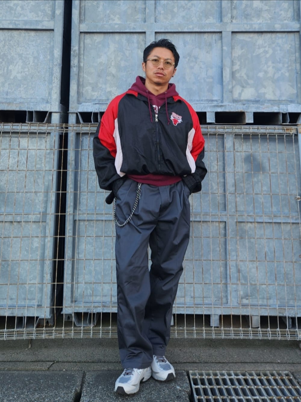 ブラック系のナイロンジャケット、レッド系のパーカー、グレー系のチノパンツを着用したメンズの秋コーディネートの1枚目の写真