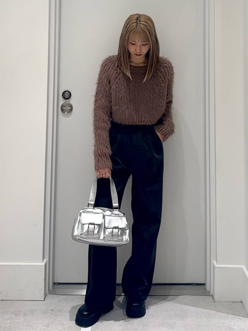 シルバー系のショルダーバッグ、ブラック系のスリッポン、ブラウン系のニット/セーターを着用したレディースの冬コーディネートの1枚目の写真