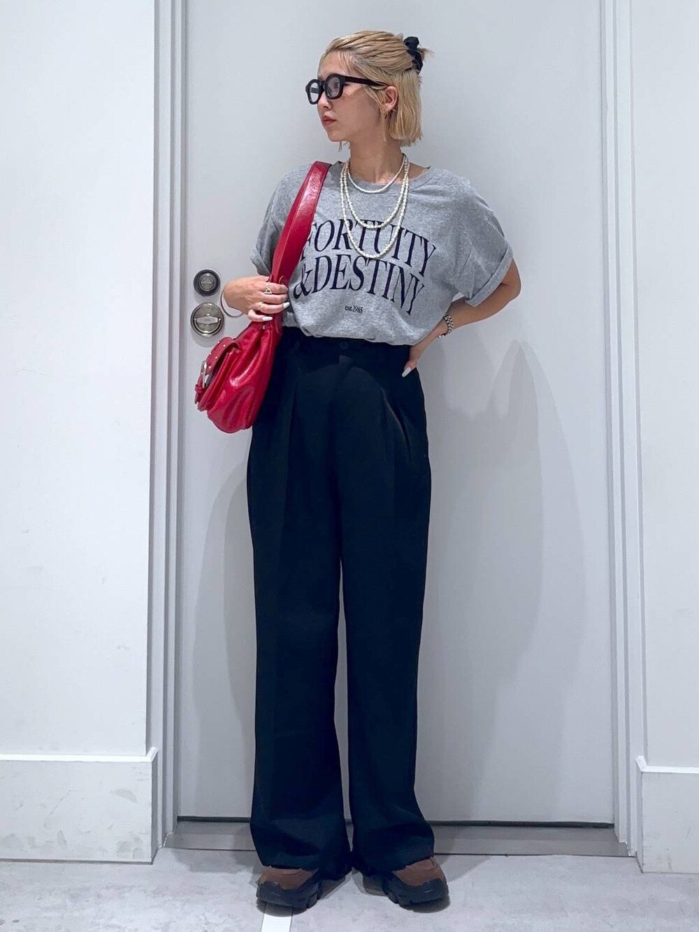 ブラウン系のモカシン/デッキシューズ、グレー系のTシャツ/カットソー、ブラック系のスラックスを着用したレディースの夏コーディネートの1枚目の写真