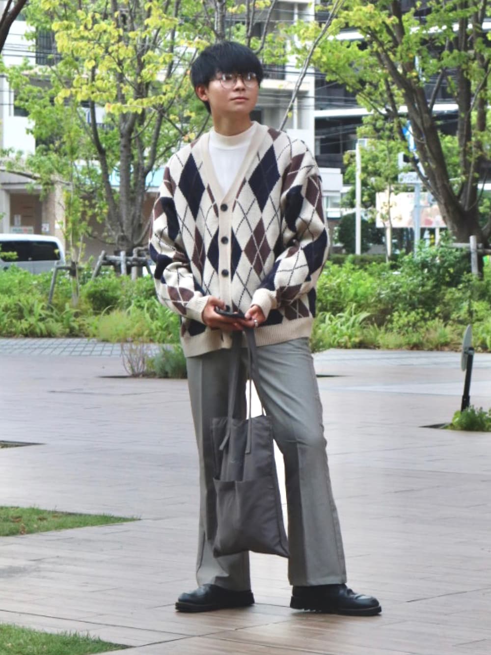 グレー系のスラックス、グレー系のトートバッグ、ホワイト系のカーディガン/ボレロを着用したメンズの秋コーディネートの1枚目の写真