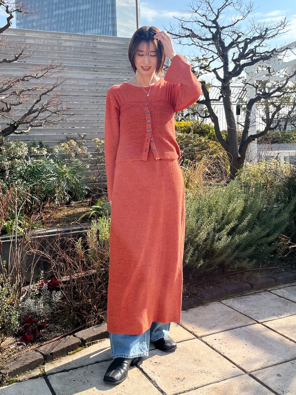 オレンジ系のワンピース、ブルー系のデニムパンツを着用したレディースの冬コーディネートの1枚目の写真