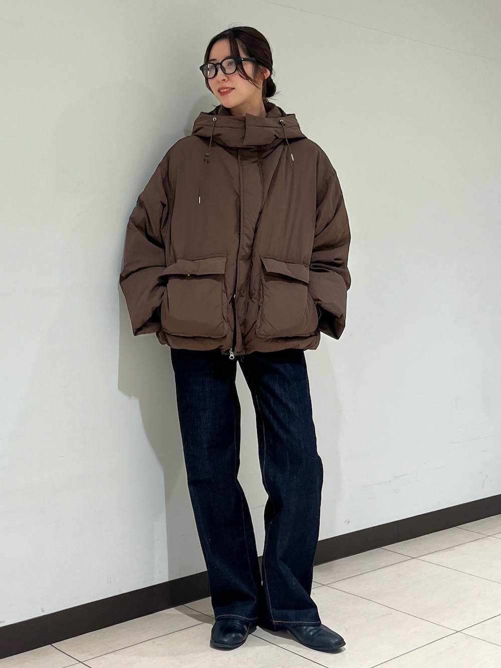 ブラウン系のダウンジャケット/コート、ブルー系のデニムパンツ、ブラック系のサングラスを着用したレディースの冬コーディネートの1枚目の写真