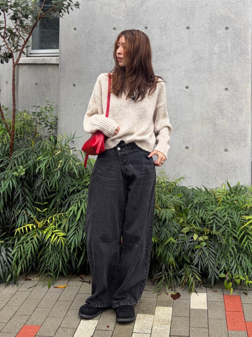 ホワイト系のニット/セーター、ブラック系のデニムパンツ、レッド系のハンドバッグを着用したレディースの秋コーディネートの1枚目の写真