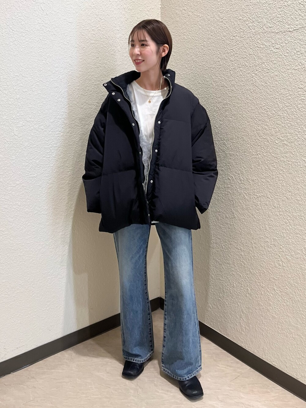 ブラック系のダウンジャケット/コート、ホワイト系のTシャツ/カットソー、グレー系のニット/セーターを着用したレディースの冬コーディネートの1枚目の写真