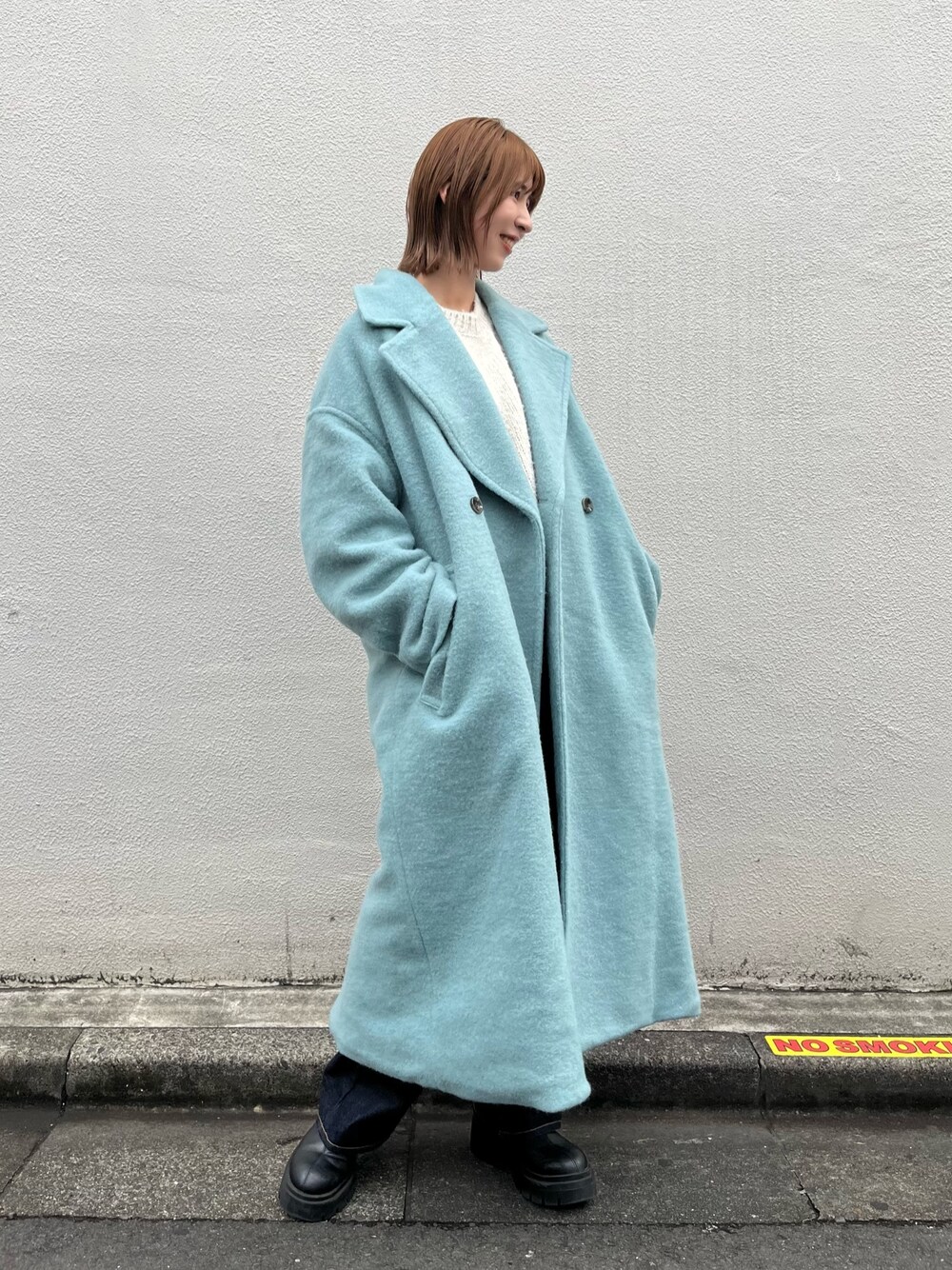 ブルー系のチェスターコート、ホワイト系のニット/セーター、ブルー系のデニムパンツを着用したレディースの秋コーディネートの1枚目の写真