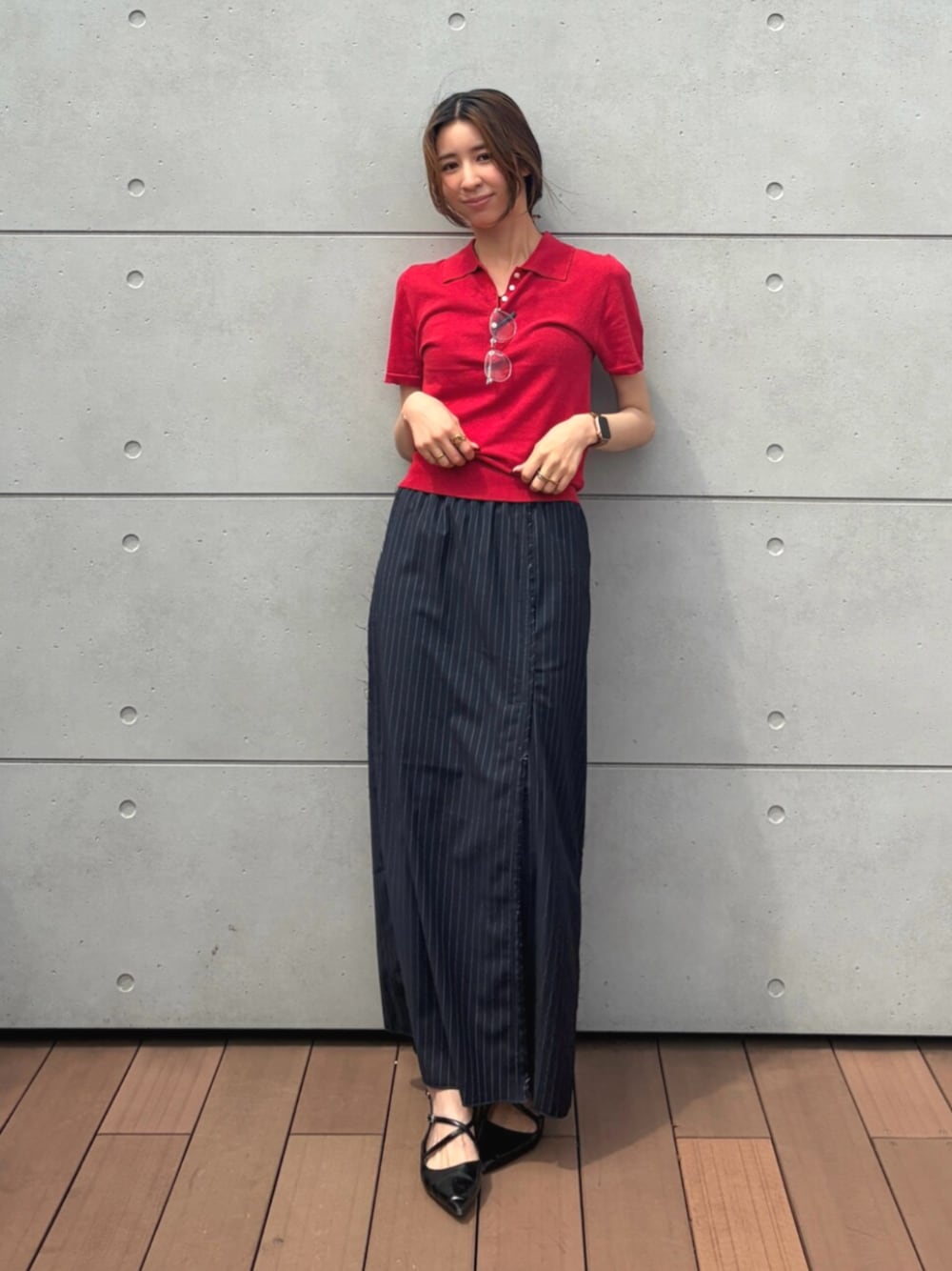 レッド系のニット/セーター、ブルー系のスカート、シルバー系のメガネを着用したレディースの夏コーディネートの1枚目の写真