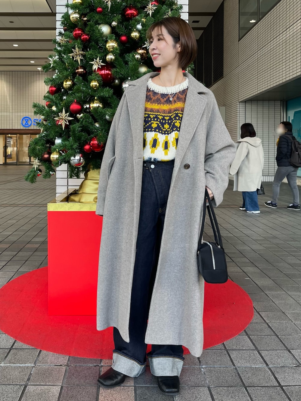 ホワイト系のニット/セーター、グレー系のチェスターコート、ブルー系のデニムパンツを着用したレディースの冬コーディネートの1枚目の写真