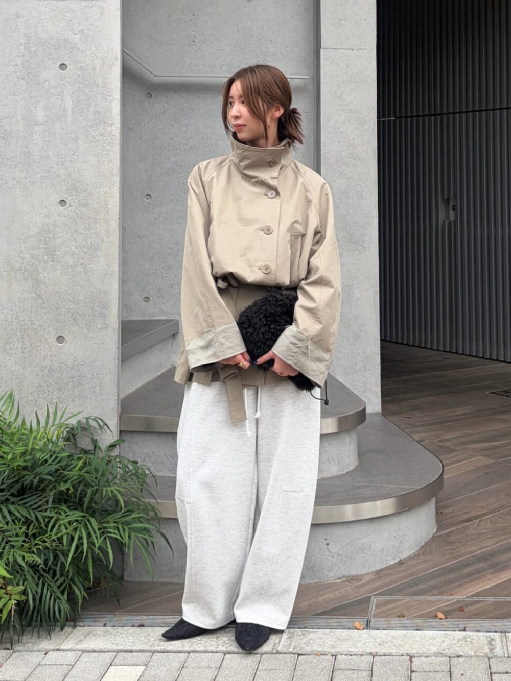 ブラック系のパンプス、ブラック系のハンドバッグ、グリーン系のトレンチコートを着用したレディースの秋コーディネートの1枚目の写真