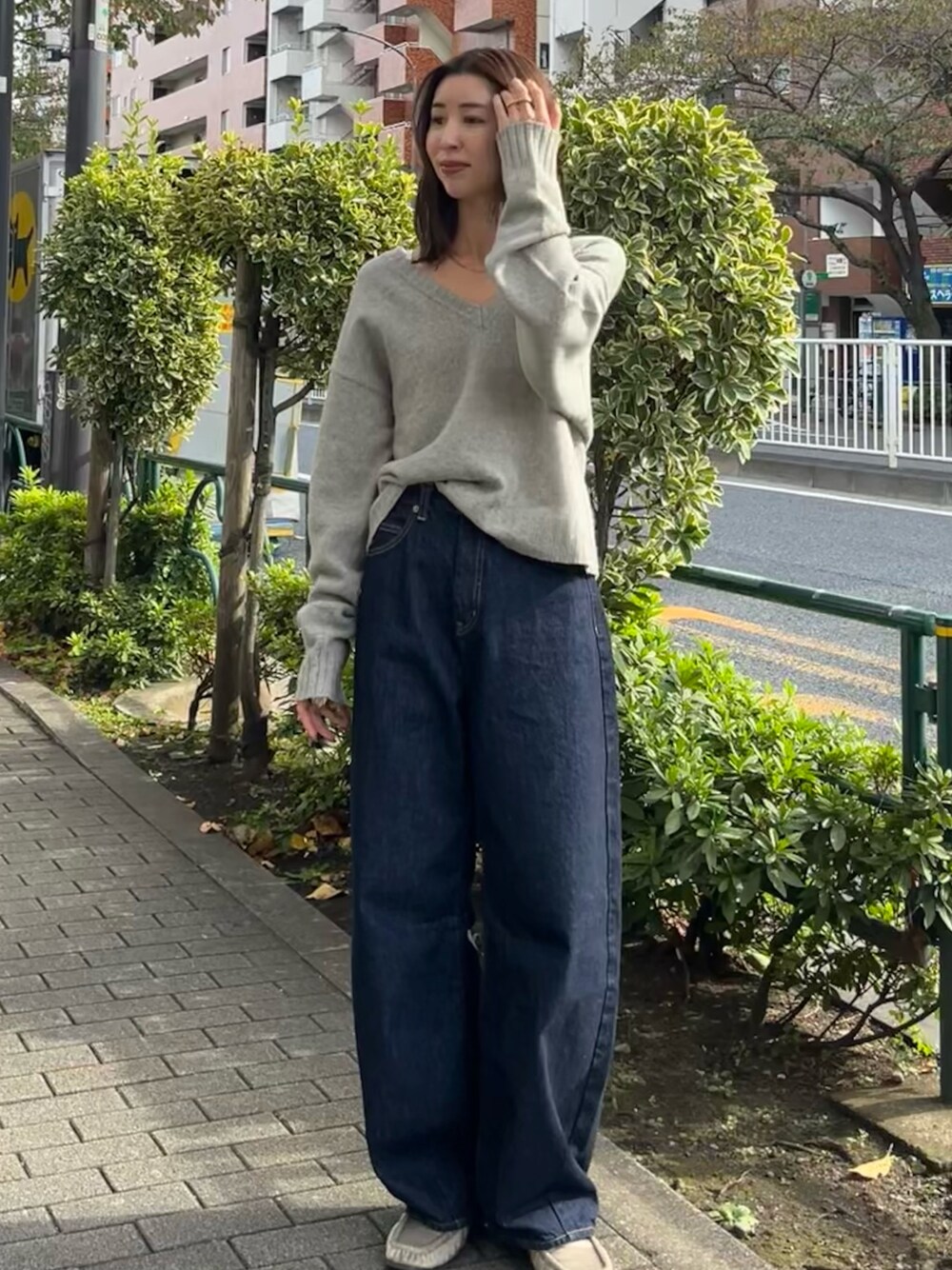 グレー系のニット/セーター、ブルー系のデニムパンツを着用したレディースの秋コーディネートの1枚目の写真