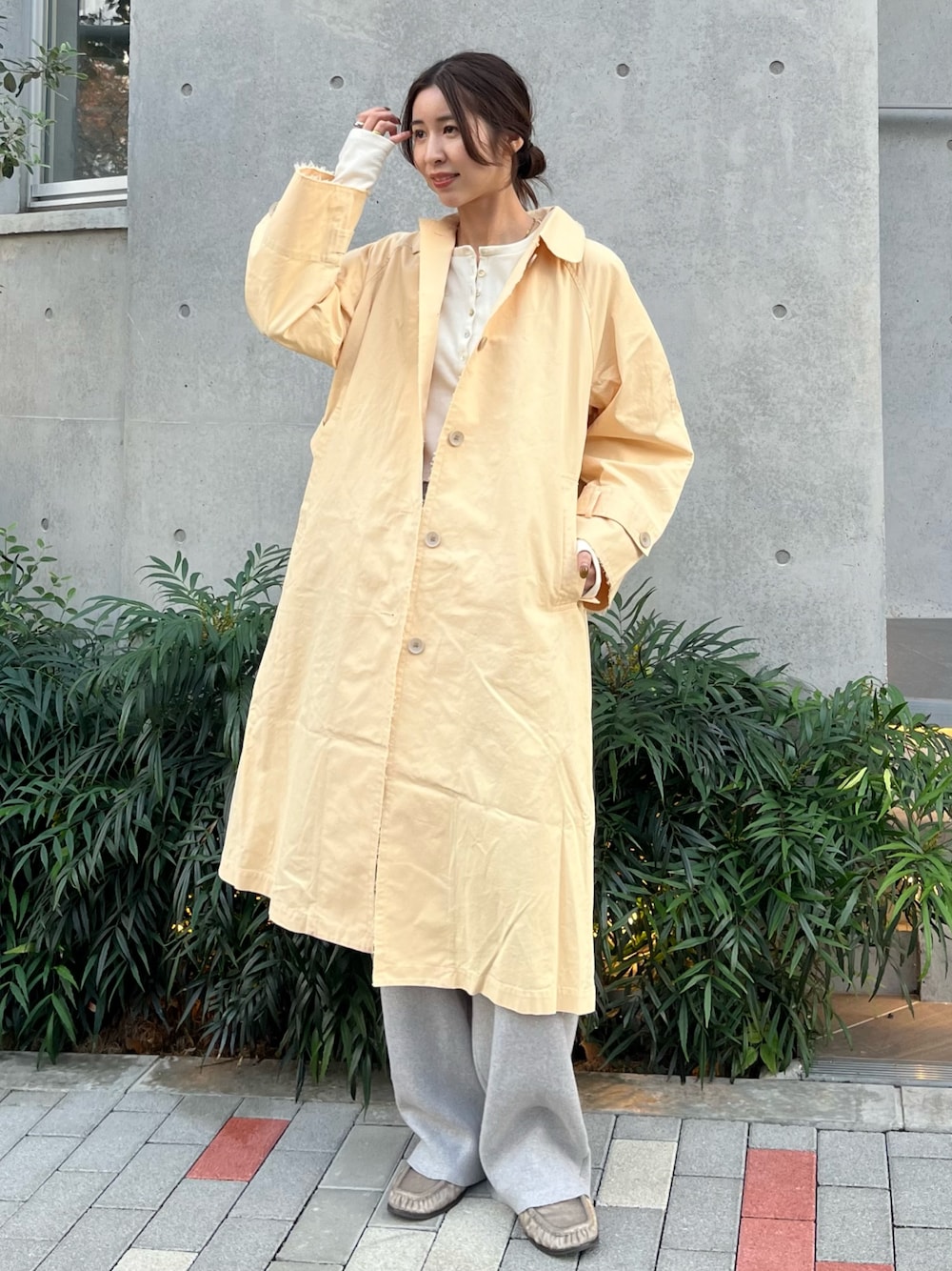 イエロー系のステンカラーコート、ホワイト系のTシャツ/カットソー、グレー系のその他パンツを着用したレディースの秋コーディネートの1枚目の写真