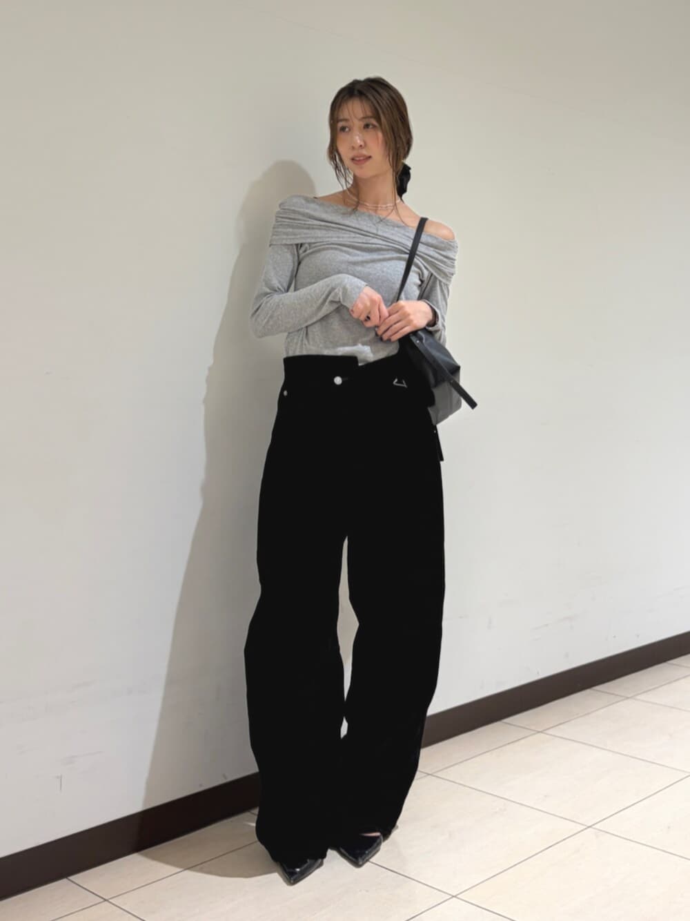 グレー系のTシャツ/カットソー、ブラック系のデニムパンツ、ブラック系のハンドバッグを着用したレディースの秋コーディネートの1枚目の写真