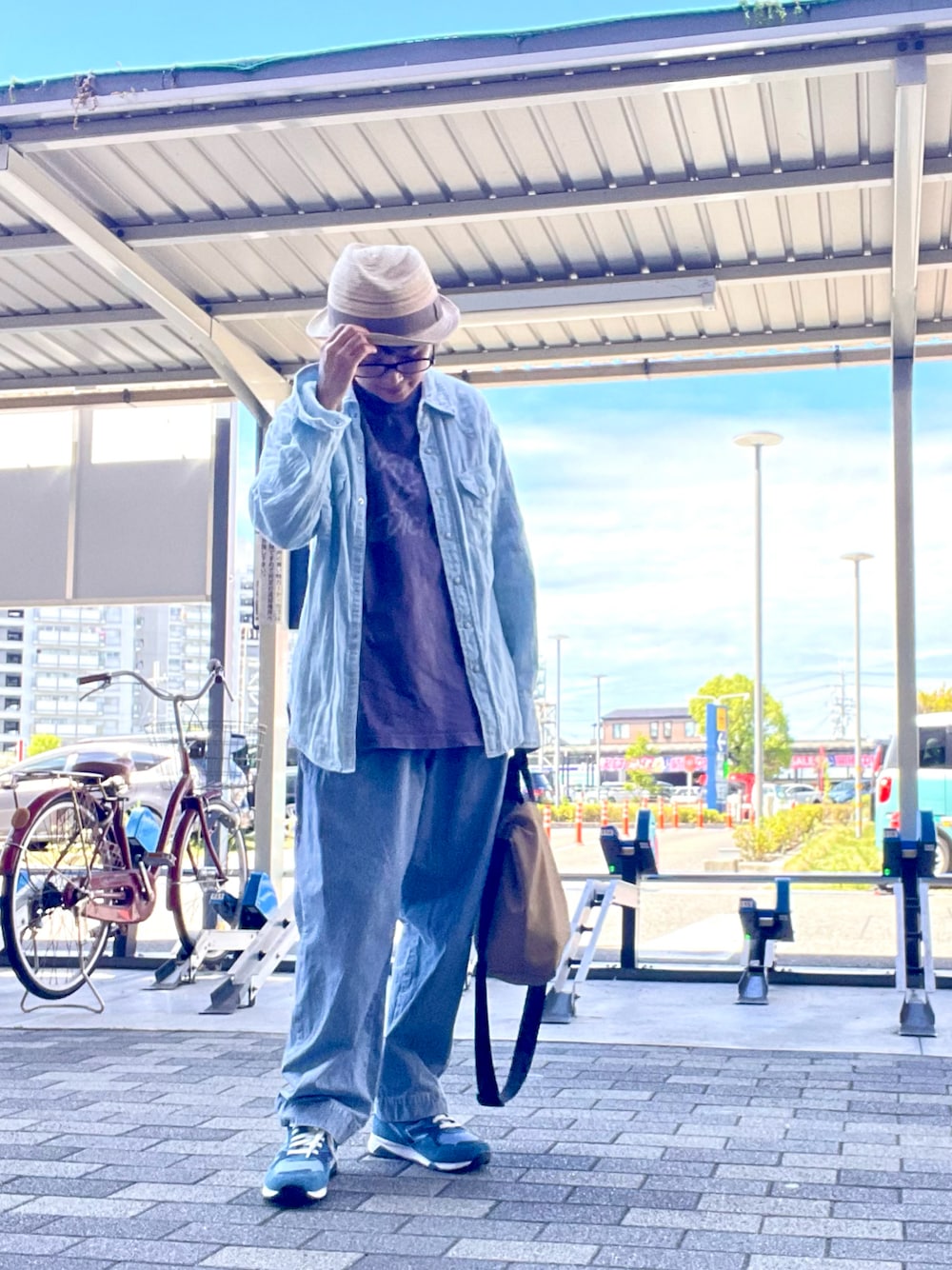 ベージュ系のショルダーバッグ、ブルー系のデニムパンツ、ブルー系のシャツ/ブラウスを着用したレディースの秋コーディネートの1枚目の写真