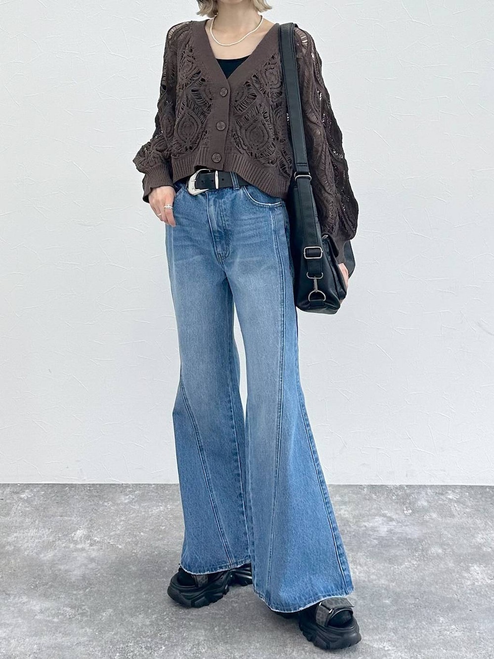 ブラック系のキャミソール、ブラウン系のカーディガン/ボレロ、ブルー系のデニムパンツを着用したレディースの春コーディネートの1枚目の写真