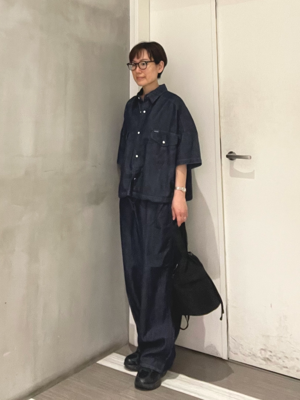ブルー系のシャツ/ブラウス、ブルー系のデニムパンツ、ブラック系のショルダーバッグを着用したレディースの春コーディネートの1枚目の写真