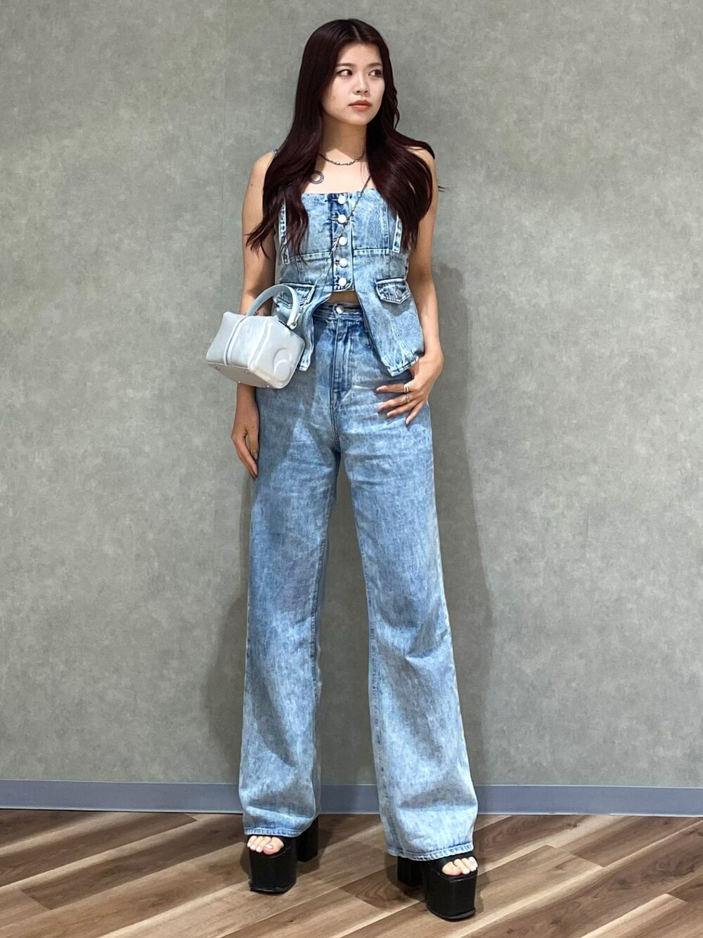 ブルー系のデニムパンツ、ブルー系のキャミソール、シルバー系のハンドバッグを着用したレディースの夏コーディネートの1枚目の写真