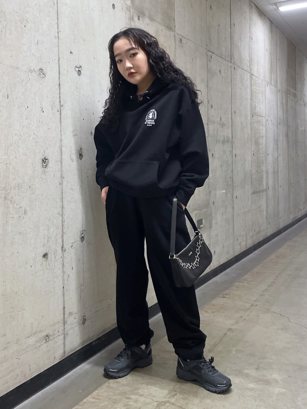 ブラック系のパーカー、ブラック系のスウェットパンツ、ブラック系のハンドバッグを着用したレディースの冬コーディネートの1枚目の写真