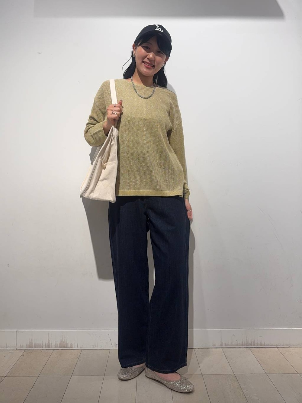 ゴールド系のバレエシューズ、イエロー系のニット/セーター、ブラック系のデニムパンツを着用したレディースの秋コーディネートの1枚目の写真