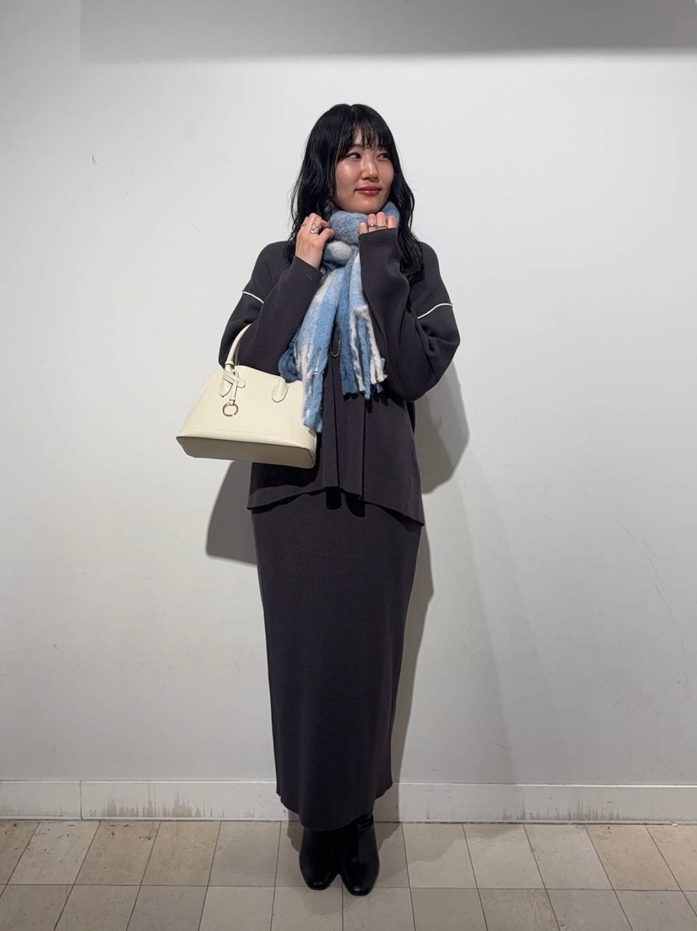 ホワイト系のショルダーバッグ、グレー系のワンピース、ブラック系のブーツを着用したレディースの秋コーディネートの1枚目の写真
