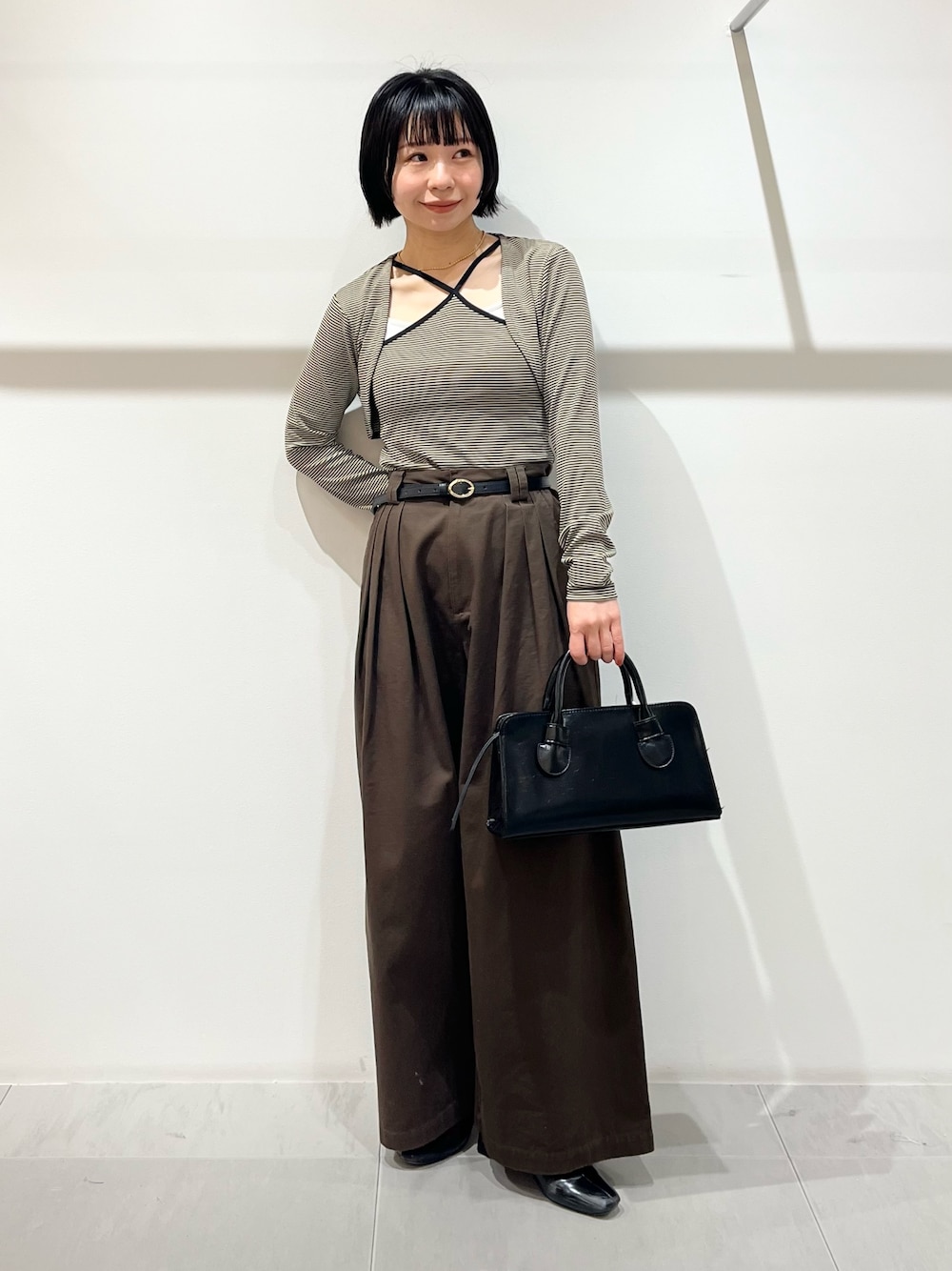 ベージュ系のキャミソール、ブラウン系のその他パンツ、ブラック系のボストンバッグを着用したレディースの春コーディネートの1枚目の写真