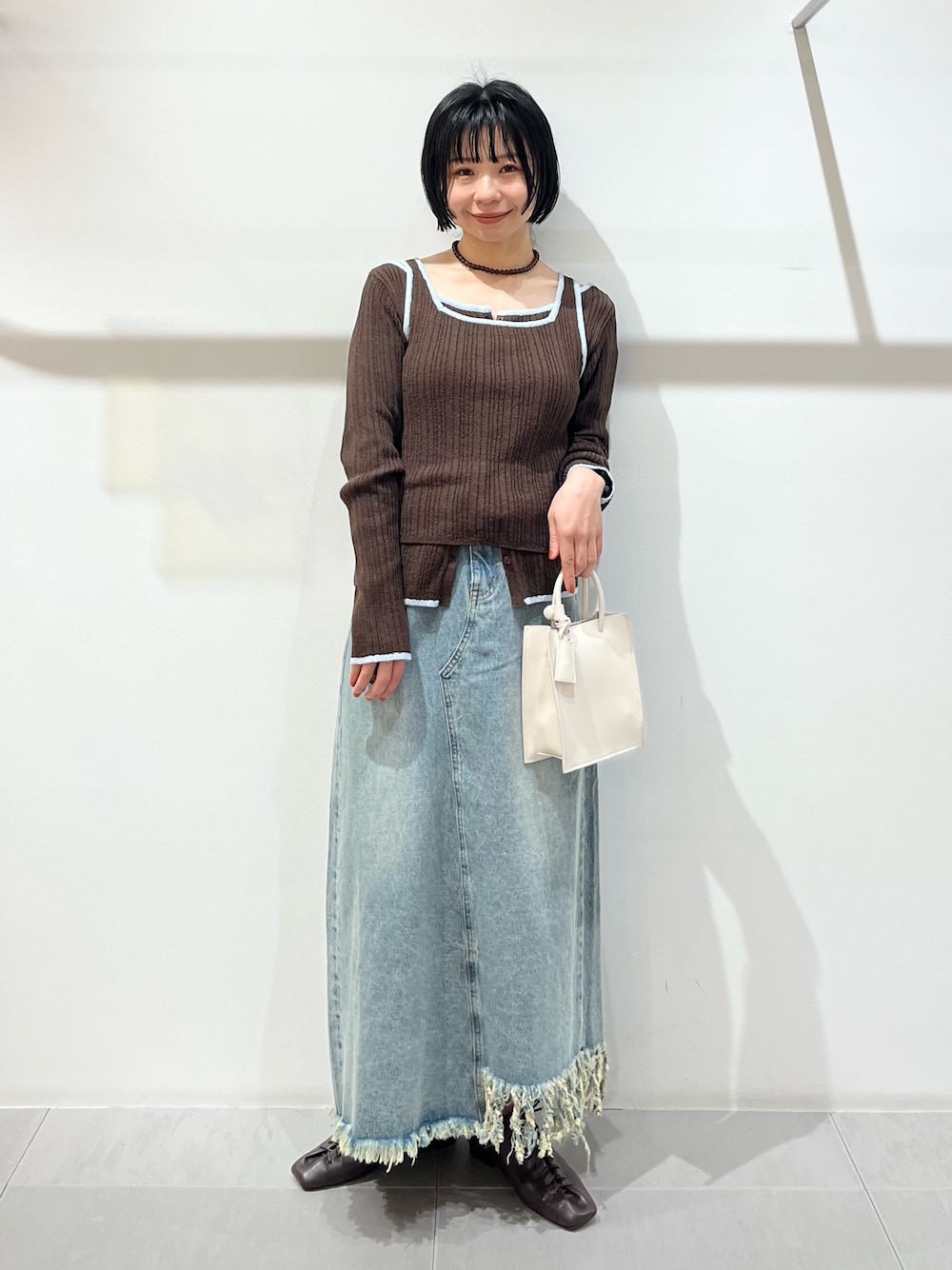 ブラウン系のその他シューズ、ブルー系のスカート、ホワイト系のハンドバッグを着用したレディースの春コーディネートの1枚目の写真