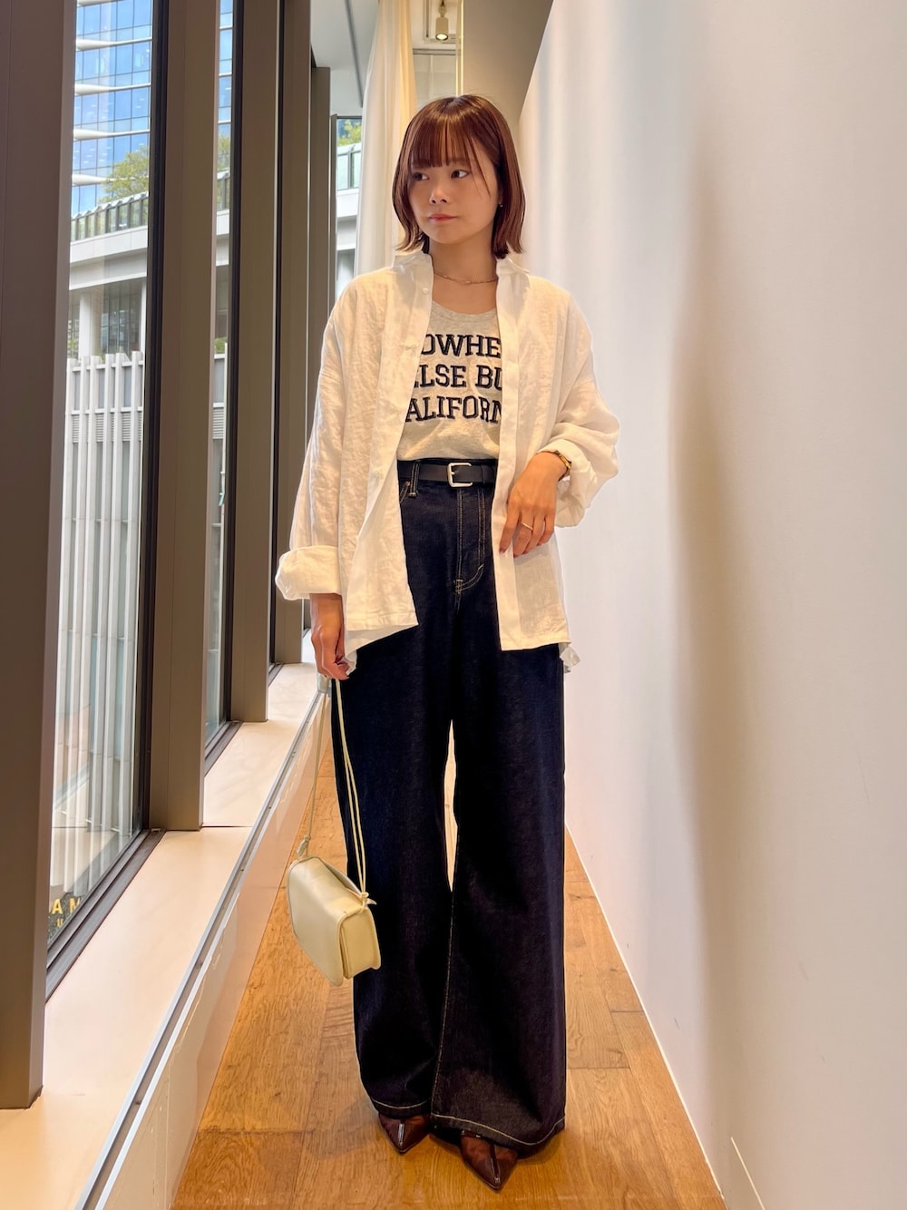ホワイト系のシャツ/ブラウス、ブルー系のデニムパンツ、ホワイト系のショルダーバッグを着用したレディースの春コーディネートの1枚目の写真