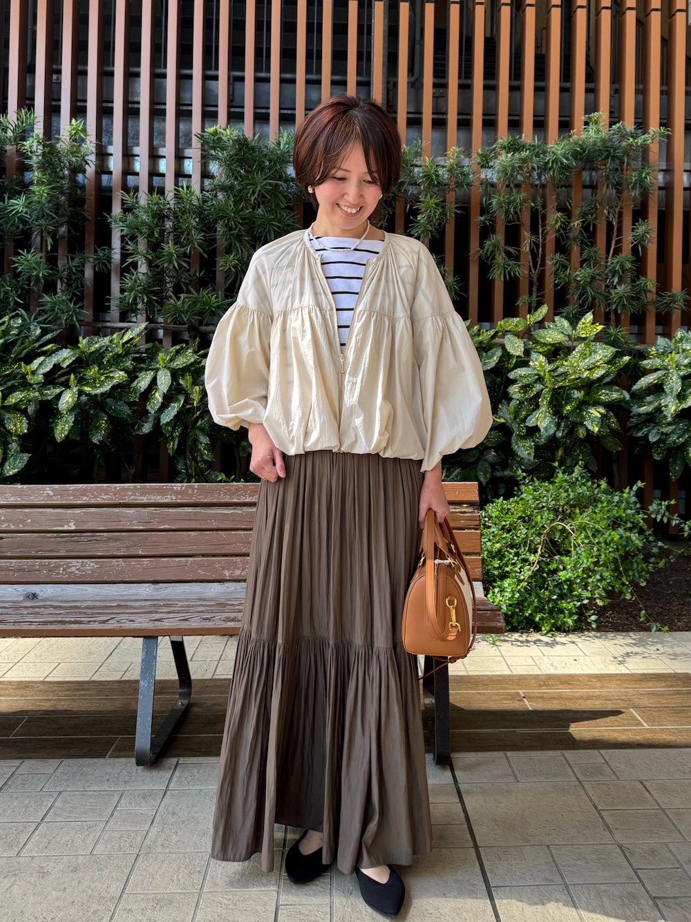ホワイト系のTシャツ/カットソー、グリーン系のスカート、ブラウン系のボストンバッグを着用したレディースの春コーディネートの1枚目の写真