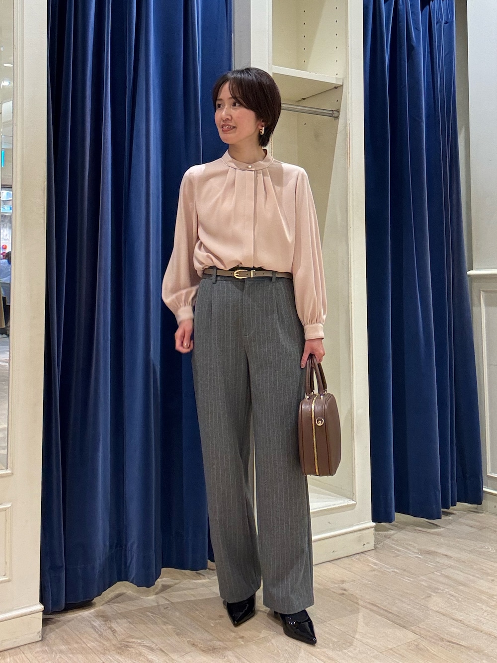 ピンク系のシャツ/ブラウス、グレー系のその他パンツ、ブラウン系のボストンバッグを着用したレディースの冬コーディネートの1枚目の写真