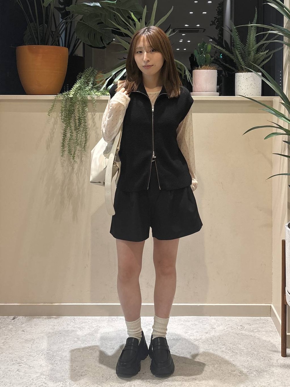 ホワイト系のショルダーバッグ、ブラック系のベスト、ホワイト系のTシャツ/カットソーを着用したレディースの秋コーディネートの1枚目の写真