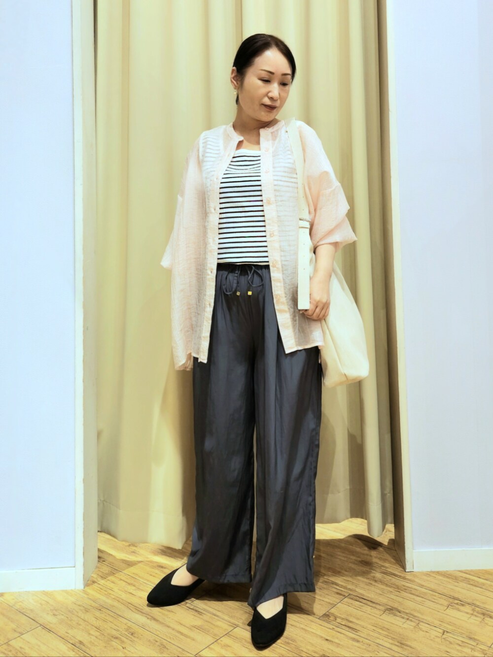 ブラック系のパンプス、グレー系のその他パンツ、ベージュ系のショルダーバッグを着用したレディースの春コーディネートの1枚目の写真