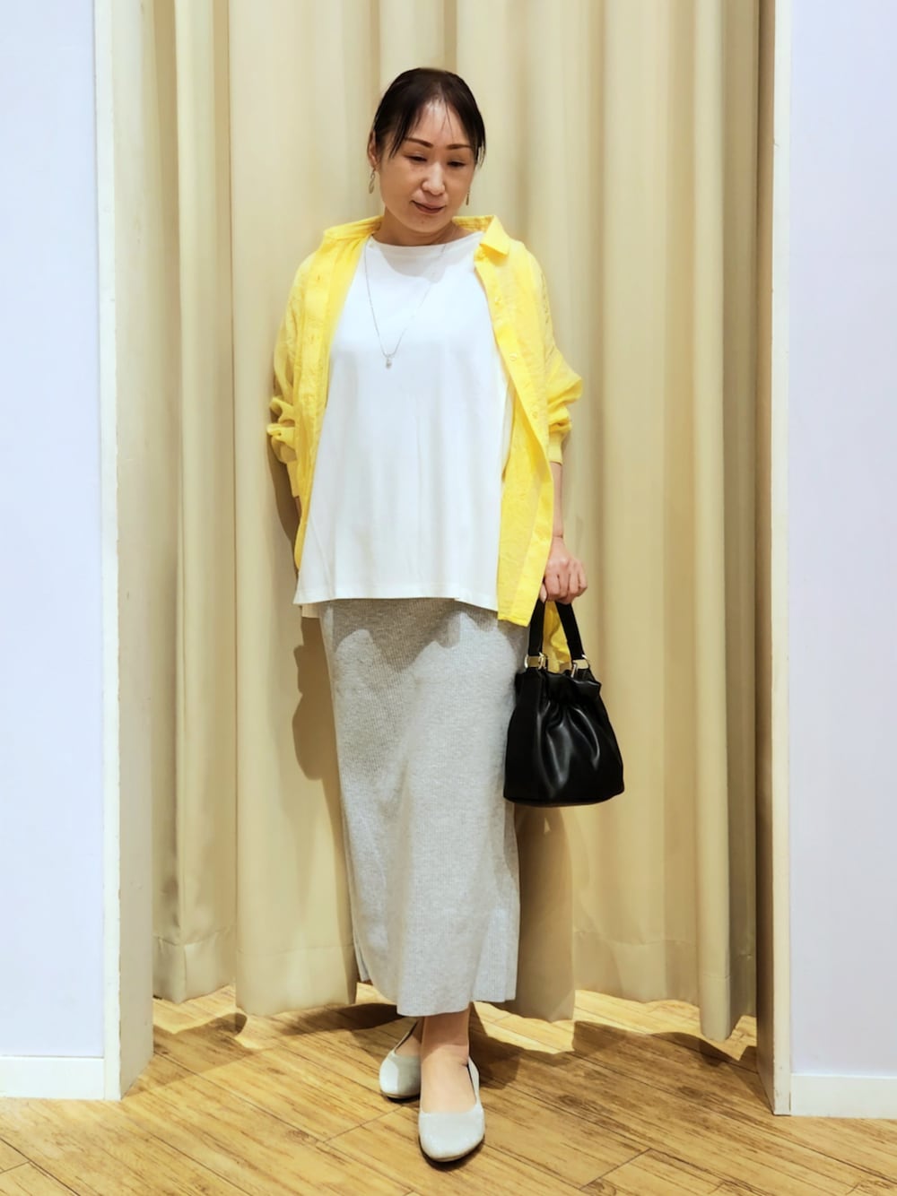 ベージュ系のパンプス、グレー系のスカート、ブラック系のショルダーバッグを着用したレディースの春コーディネートの1枚目の写真