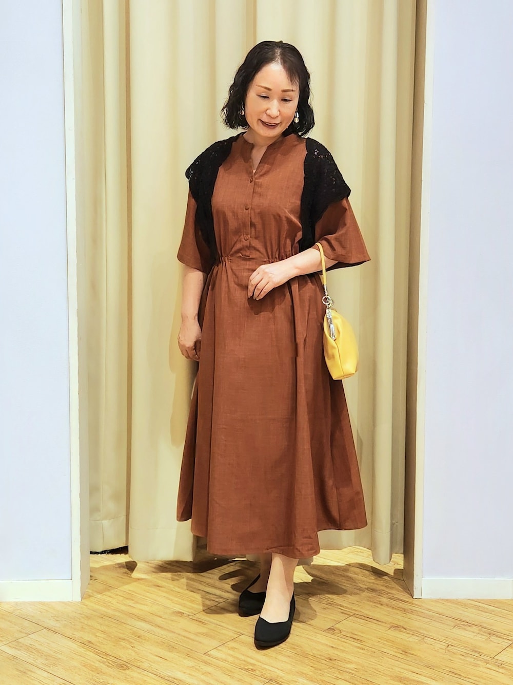 イエロー系のショルダーバッグ、ブラック系のパンプス、オレンジ系のワンピースを着用したレディースの夏コーディネートの1枚目の写真