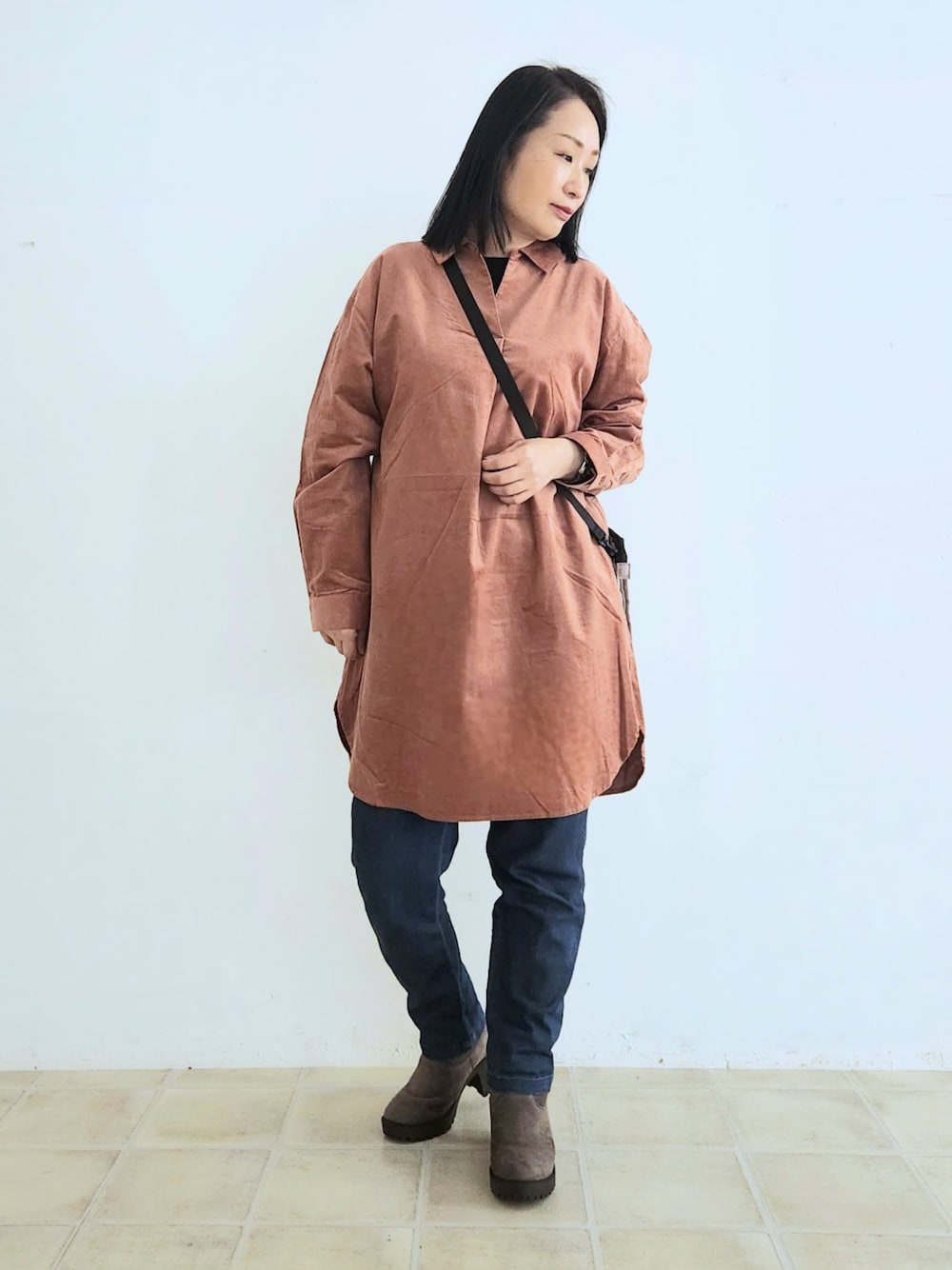 ブルー系のデニムパンツ、ブラック系のTシャツ/カットソー、ピンク系のチュニックを着用したレディースの秋コーディネートの1枚目の写真