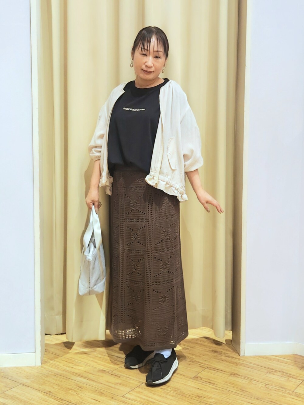 ブラック系のスニーカー、ブラウン系のスカート、ブラック系のTシャツ/カットソーを着用したレディースの夏コーディネートの1枚目の写真