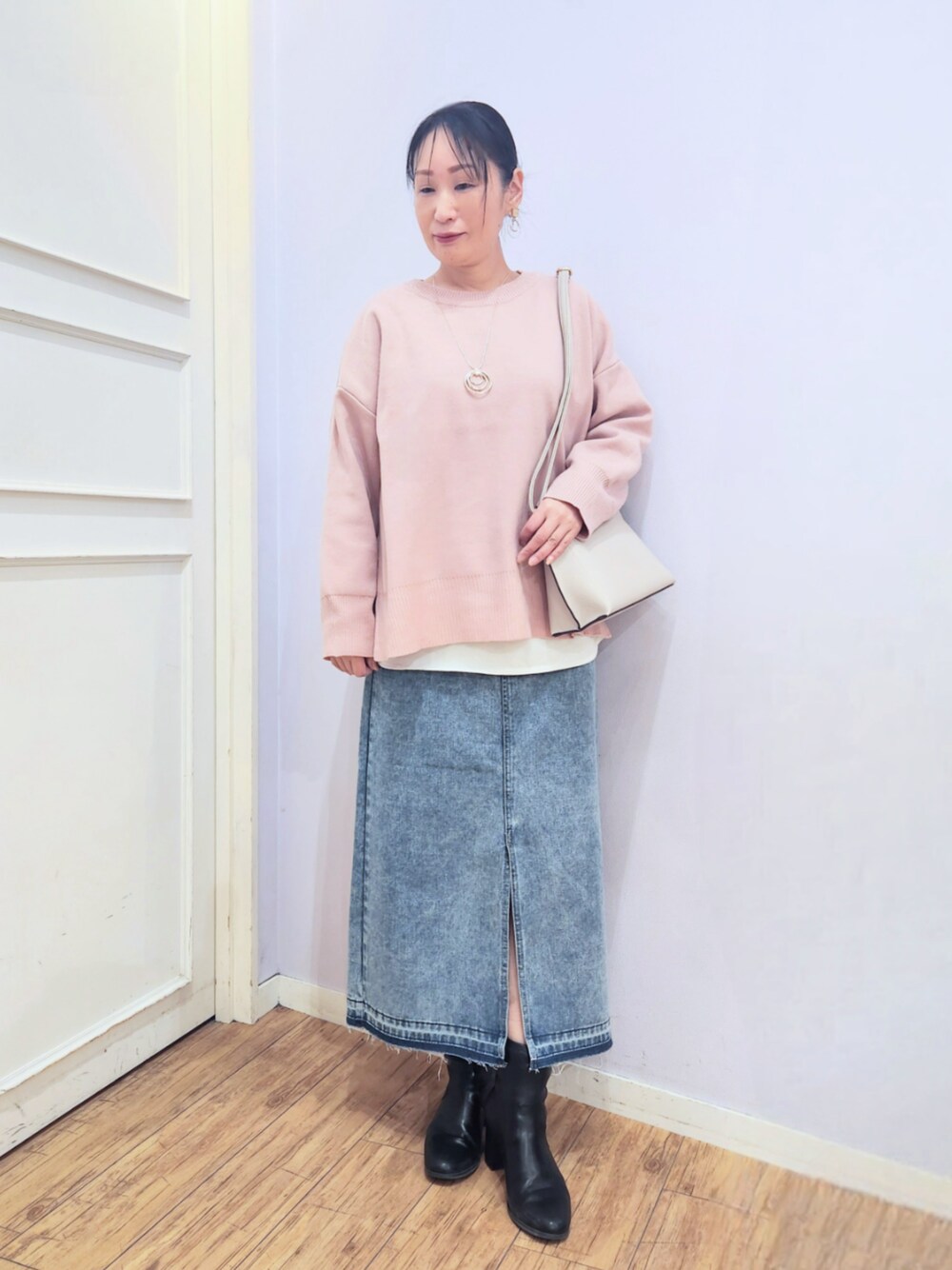 ブラック系のブーツ、ブルー系のデニムスカート、ピンク系のニット/セーターを着用したレディースの冬コーディネートの1枚目の写真