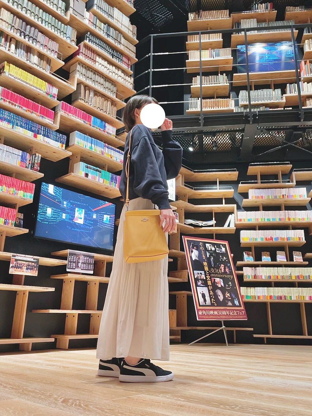 ベージュ系のスカート、イエロー系のバッグ、ブルー系のトップスを着用したレディースの春コーディネートの1枚目の写真