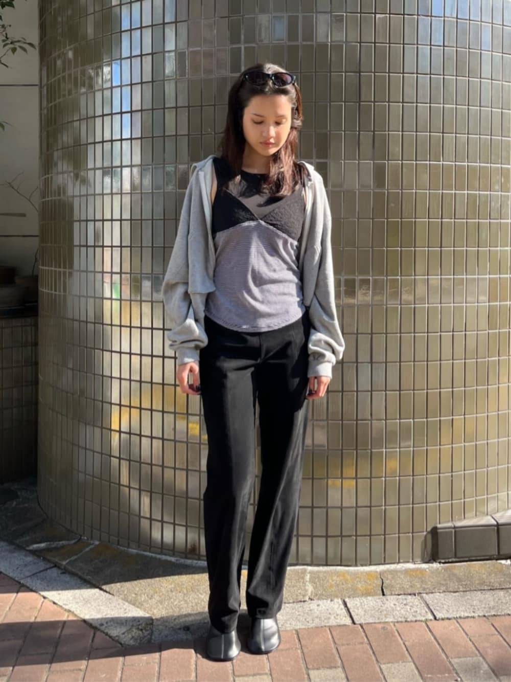 グレー系のパーカー、ブラック系のキャミソール、ブラック系のその他パンツを着用したレディースの春コーディネートの1枚目の写真
