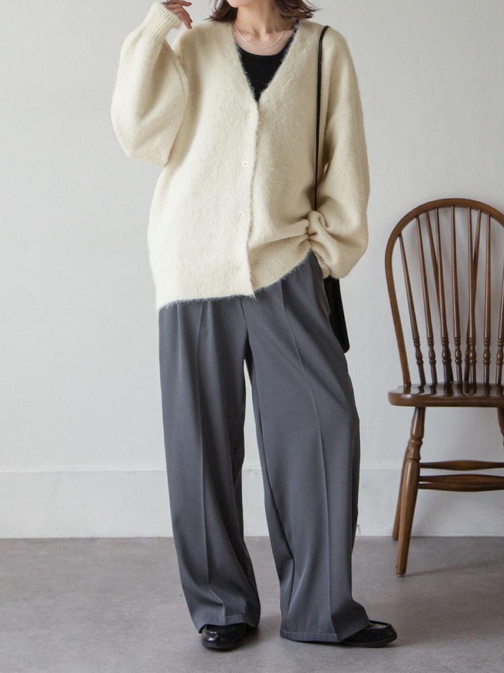 ホワイト系のカーディガン/ボレロ、グレー系のスラックスを着用したレディースの秋コーディネートの1枚目の写真